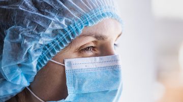 Portrait of a doctor woman in a medical mask and a protective cap.