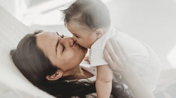 Mother kissing baby daughter hammock in natural light studio